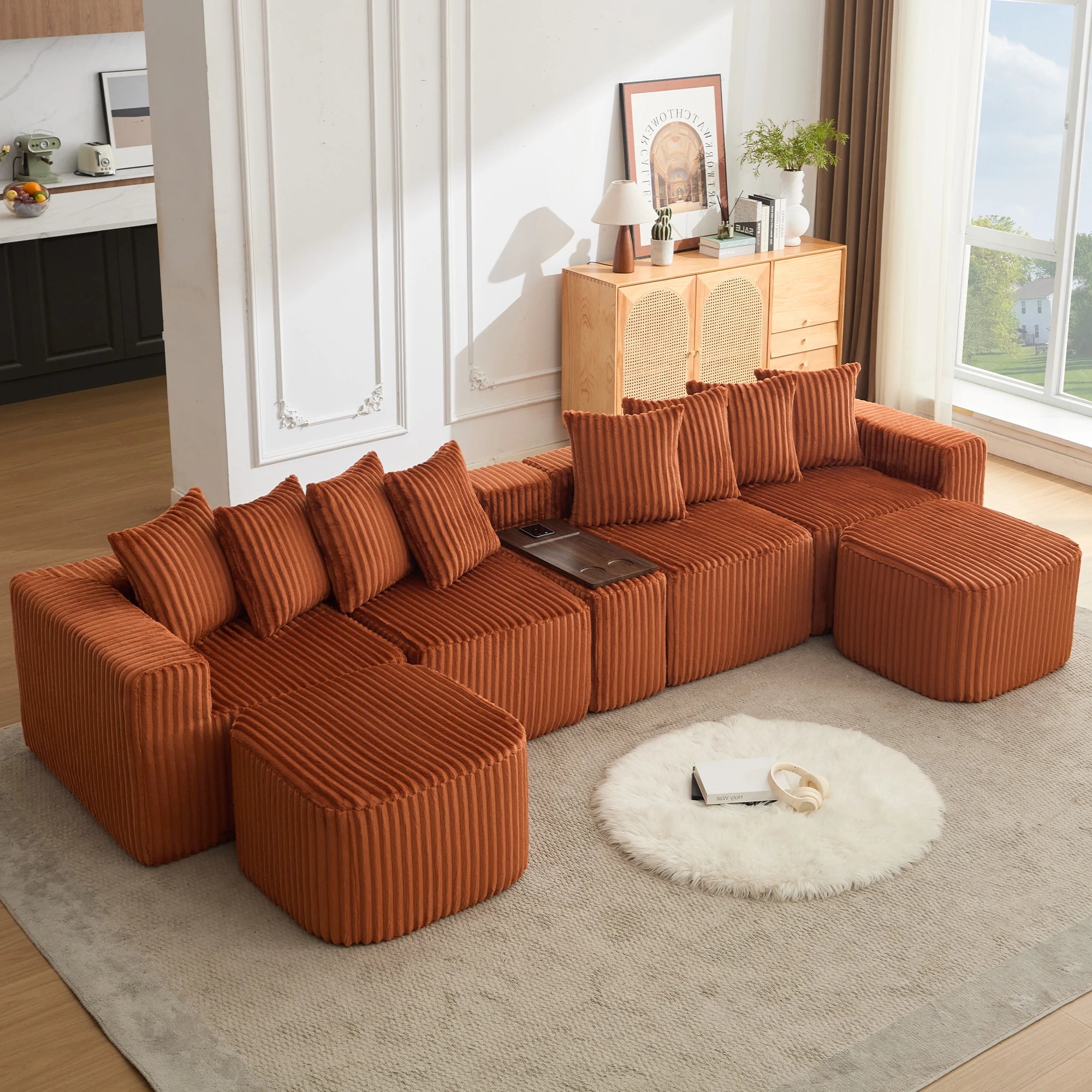 An_oversized_orange_u_shaped_sofa_in_soft_corduroy_featuring_movable_modular_seating_a_footstool_USB_and_wireless_charging_plus_a_coffee_table_board_with_cup_holders_for_stylish_every